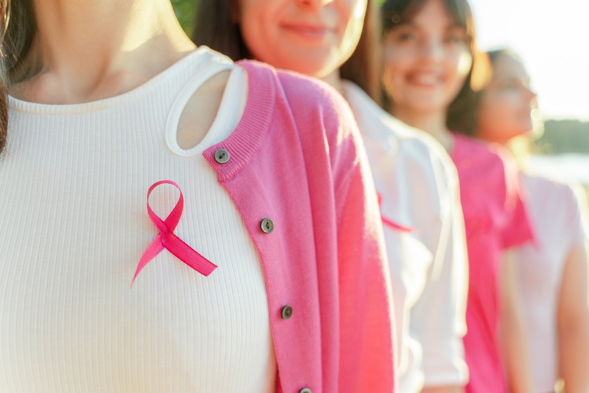 Cropped view of happy smiling women with pink ribbon on t shirts standing